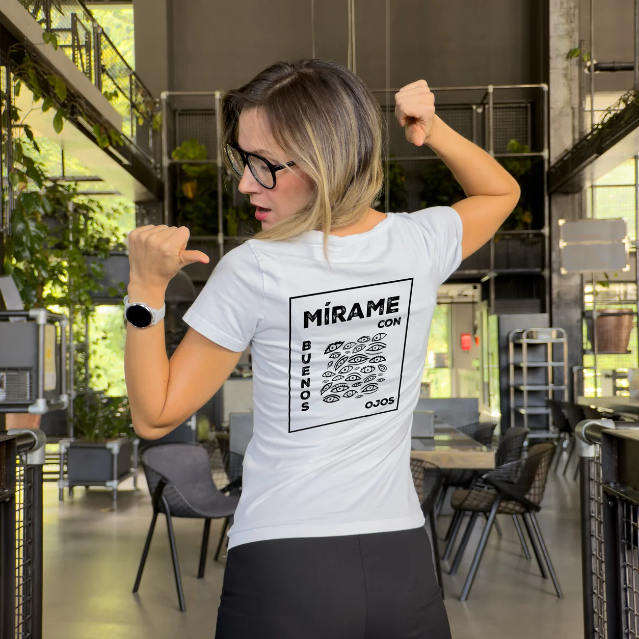 Accomplice flexing her arm in a white t-shirt with the MÍRAME artwork print