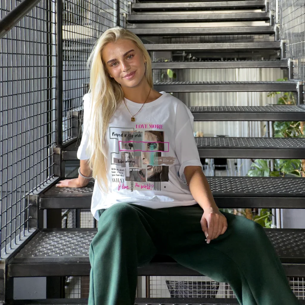 Model seated on an industrial staircase in a t-shirt with a pink artwork print