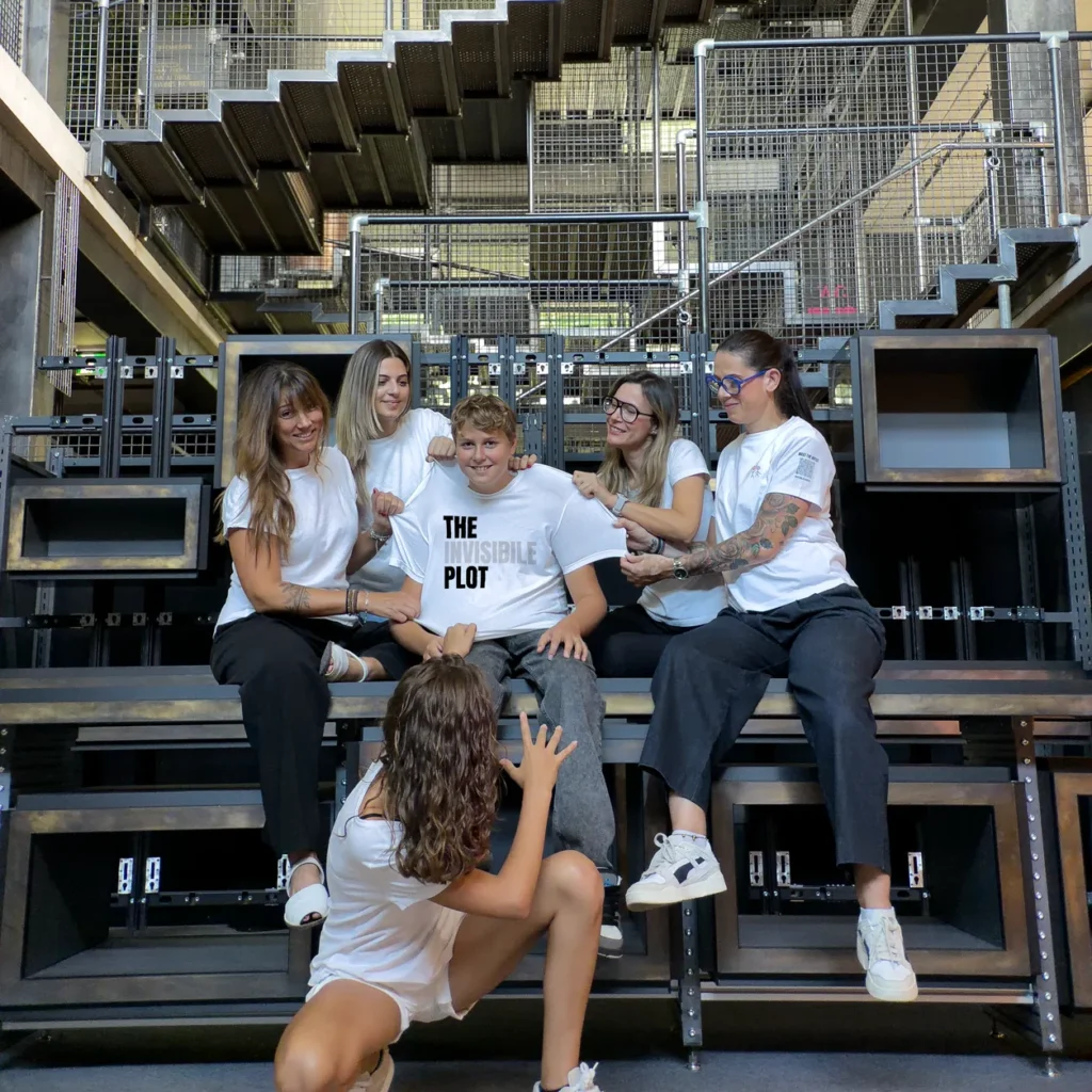 Accomplices wearing t-shirts with artist designs from The Invisible Plot — group on an industrial staircase