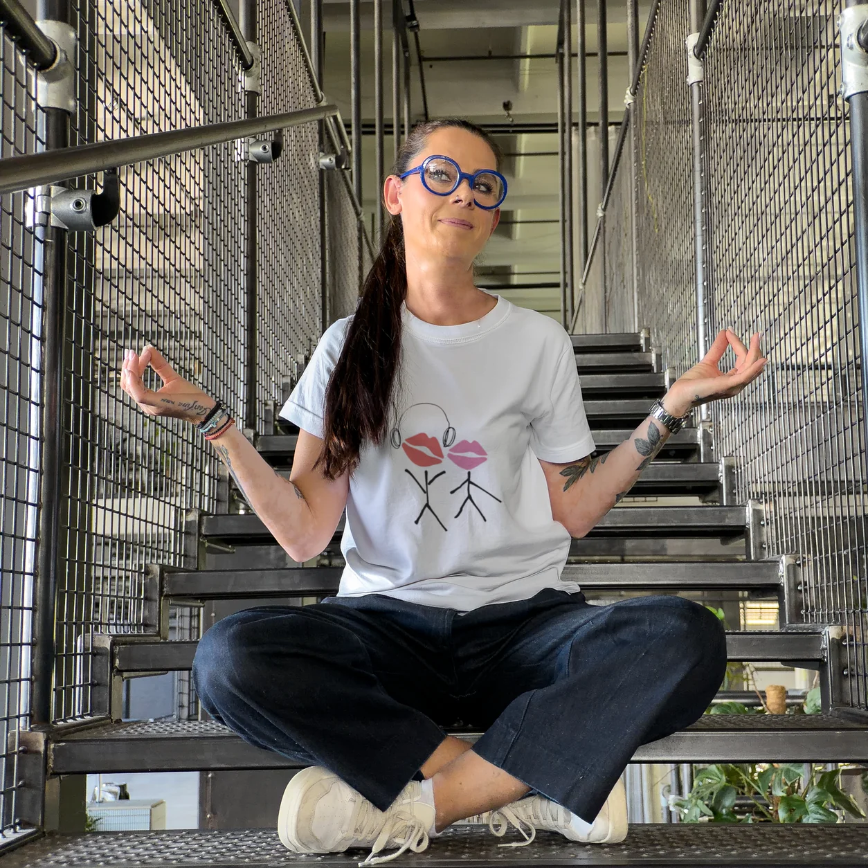 Model in a meditation pose wearing a white t-shirt with a red artwork print